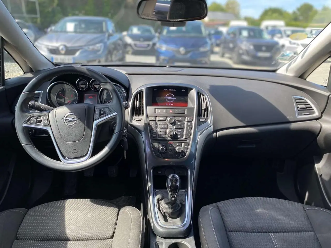 Vue intérieure avant de l'Opel Astra Sports Tourer 2014, tableau de bord gris avec volant multifonction et boîte manuelle.