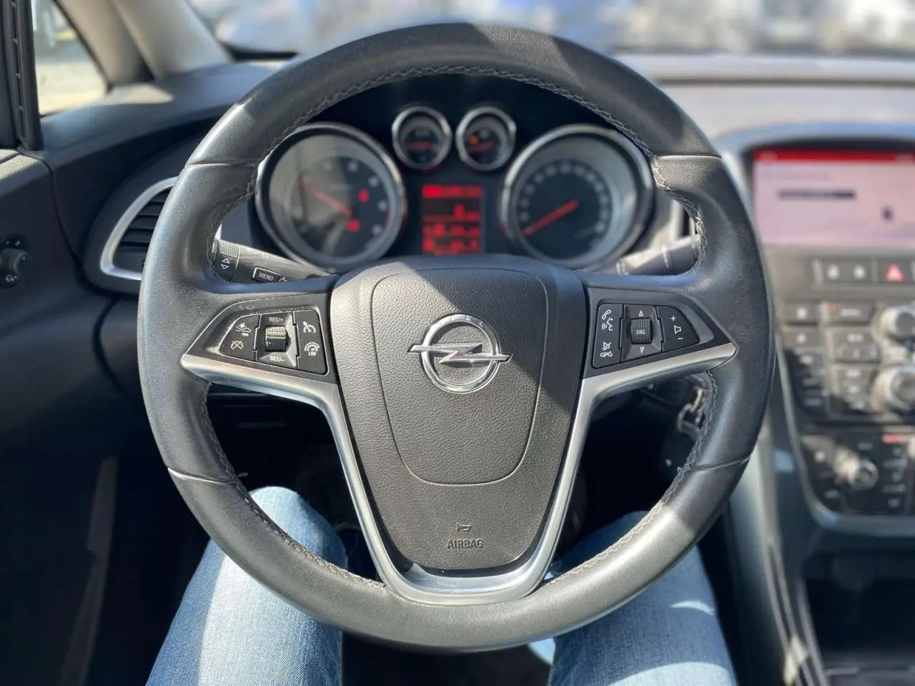 Vue intérieure centrée sur le volant noir de l’Opel Astra Sports Tourer 2014 avec commandes intégrées au tableau de bord.
