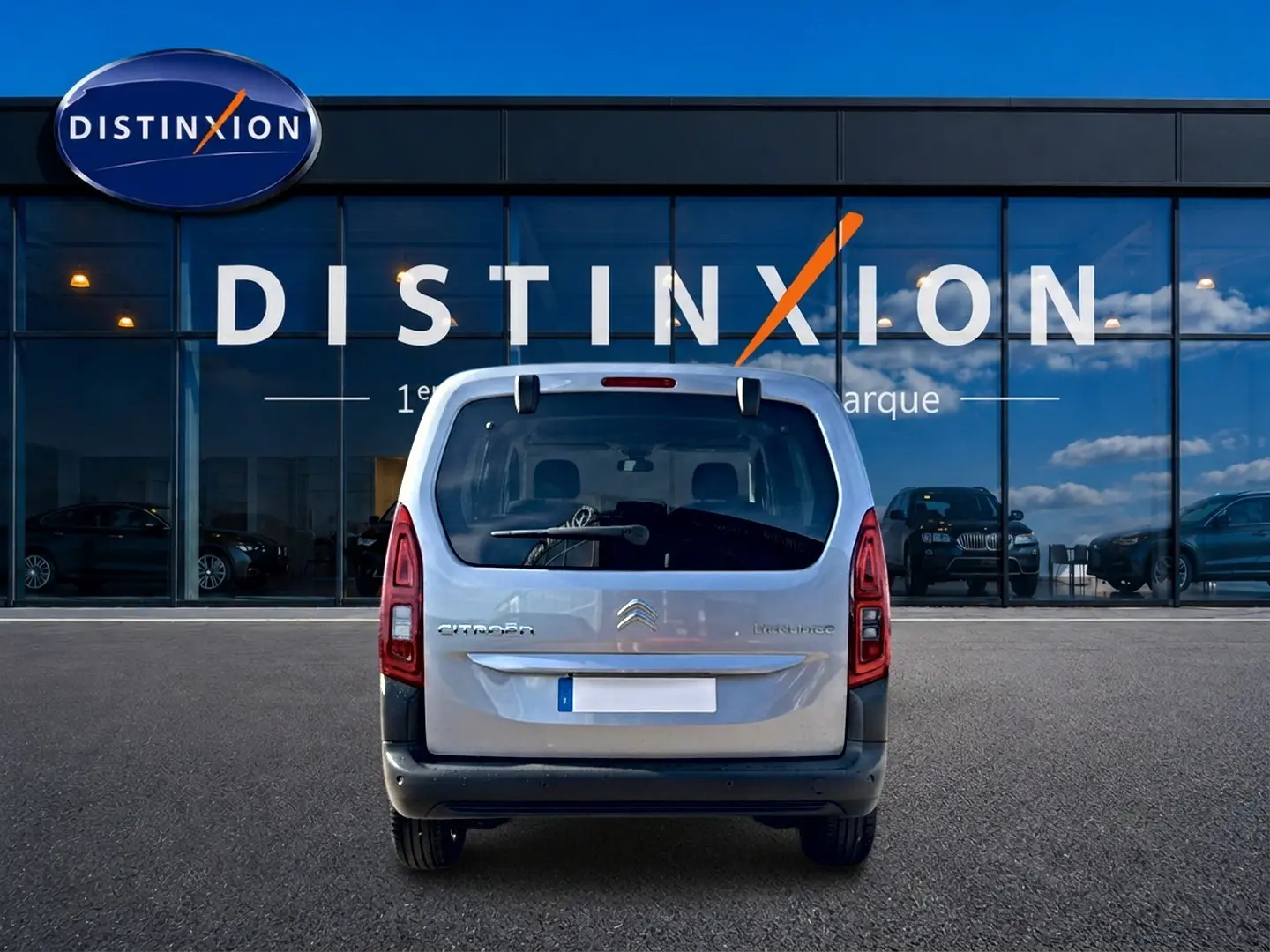 Vue arrière d’un Citroën Berlingo 2026 gris acier, avec feux verticaux et logo distinctif sur fond de vitrine Distinxion.