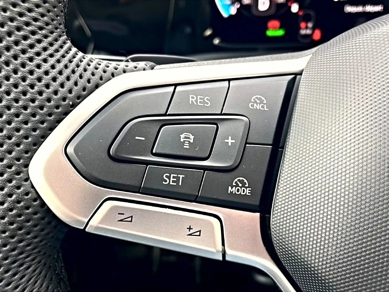 Gros plan sur les commandes de régulateur de vitesse au volant cuir perforé de la Volkswagen Golf noire 2026.