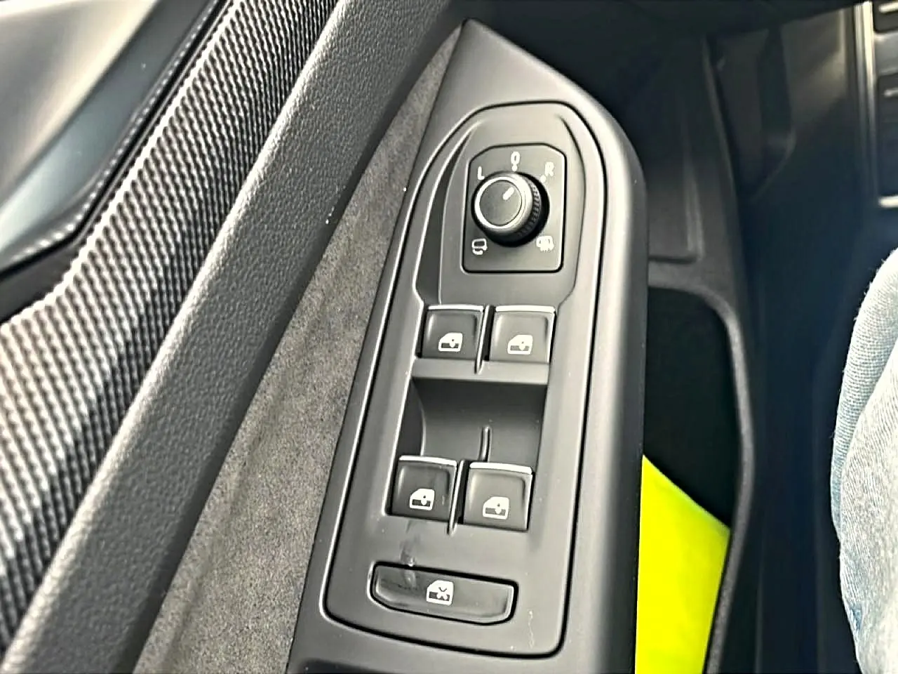 Vue rapprochée du panneau de commandes des vitres et rétroviseurs côté conducteur d’une Volkswagen Golf noire.