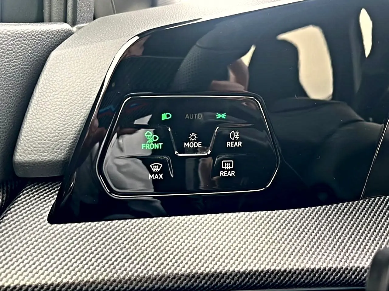 Gros plan sur les commandes d’éclairage et de dégivrage avec finition noire brillante et insert carbone dans une Volkswagen Golf noire 2026.