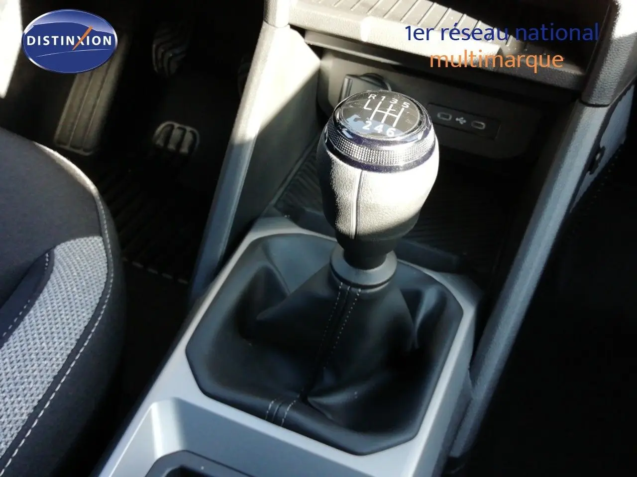 Gros plan sur le levier de vitesses manuel du Dacia Duster gris schiste, avec coutures apparentes et console noire environnante.