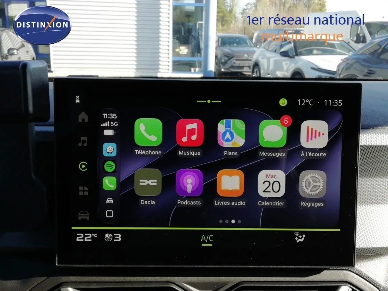 Écran tactile central du Dacia Duster 2026 affichant les applications connectées, avec tableau de bord gris en arrière-plan.