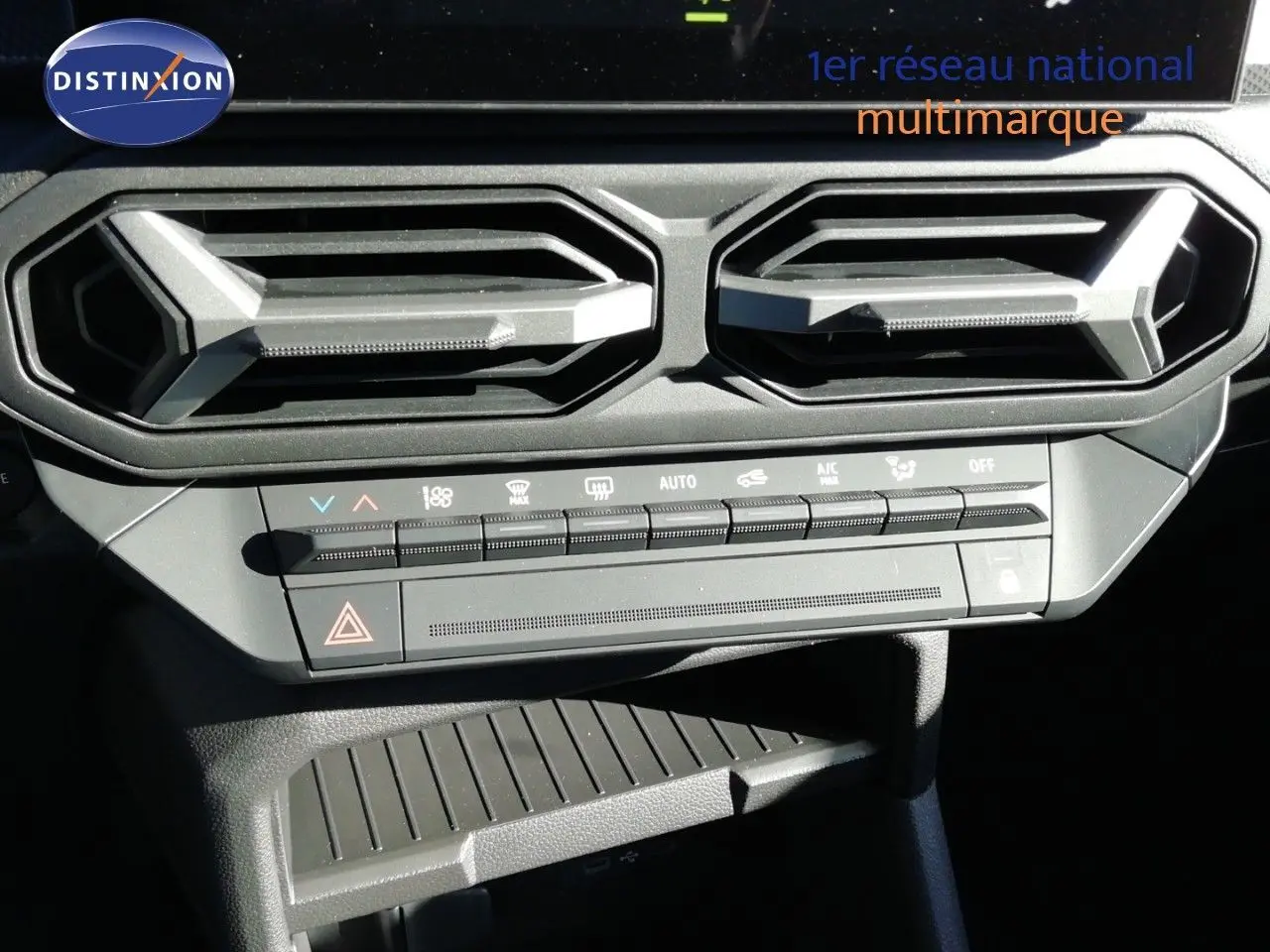 Vue rapprochée des commandes de climatisation et des aérateurs hexagonaux du Dacia Duster gris schiste métal 2026.