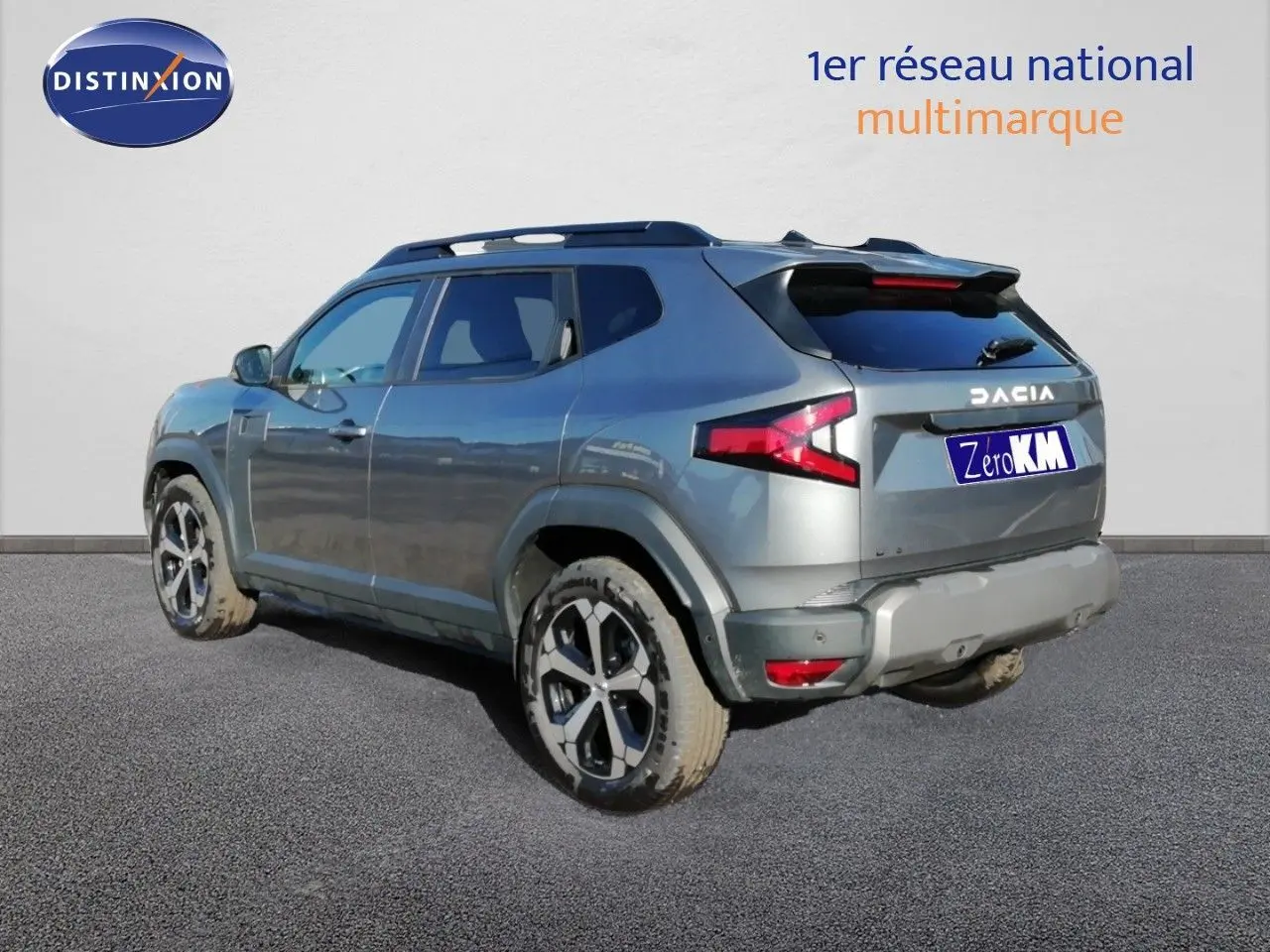 Vue 3/4 arrière droite du Dacia Duster TCE MHEV 140ch Journey en gris schiste métal avec jantes bi-ton et barres de toit.