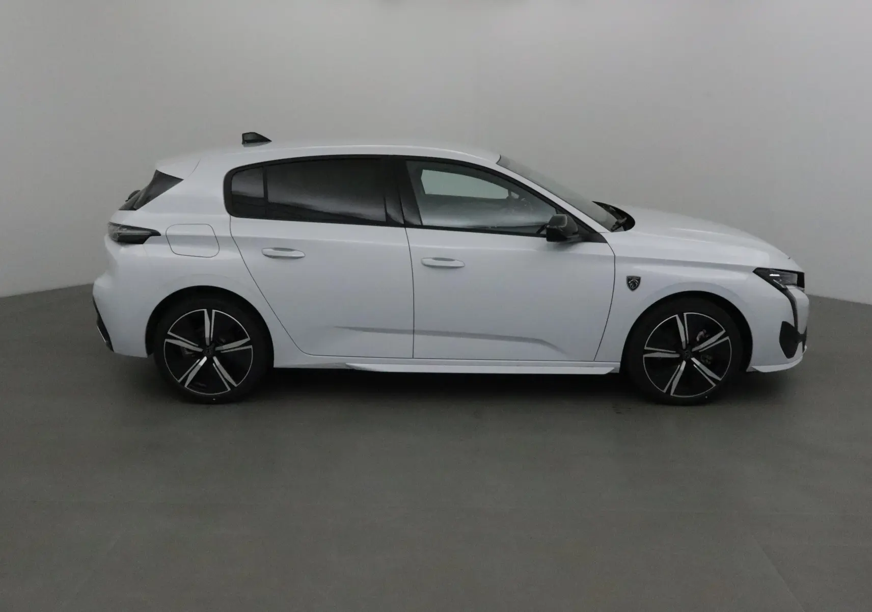 Profil côté droit d'une Peugeot 308 blanche Okenite 2025 avec jantes alliage noires et vitres teintées.