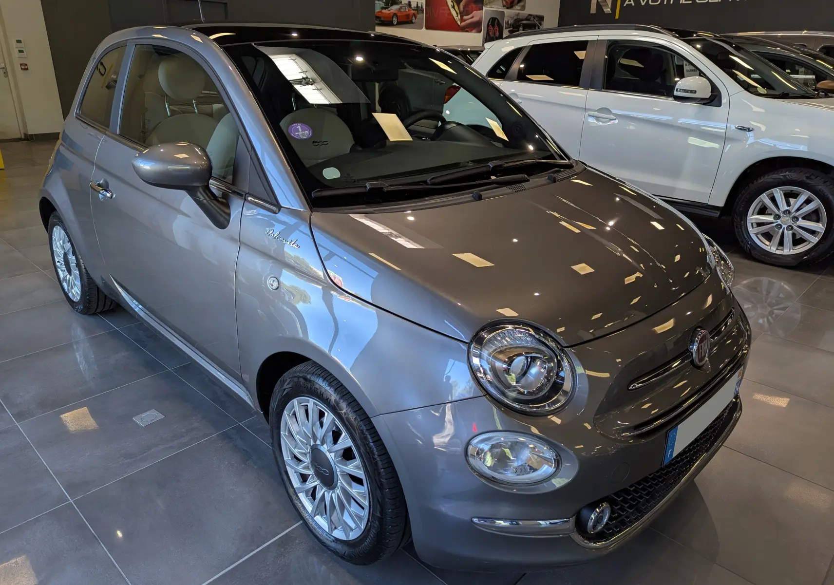 Vue 3/4 avant droite d'une Fiat 500 hybride 2021 en Electroclash Grey, avec jantes alliage et intérieur clair visible.