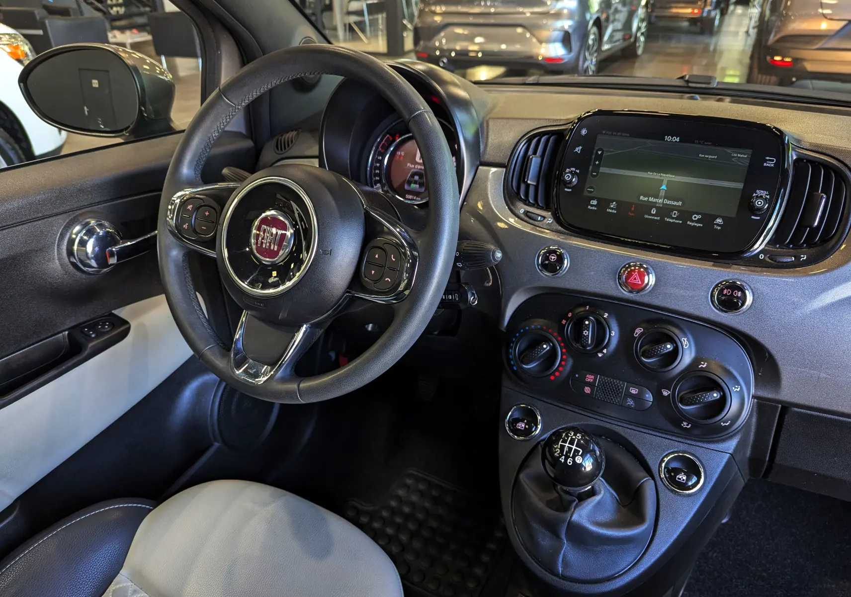 Intérieur de la Fiat 500 Electroclash Grey 2021, vue du poste de conduite avec volant, tableau de bord et levier de vitesses manuel.