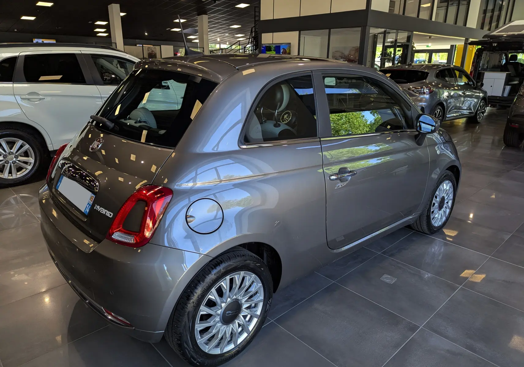 Vue 3/4 arrière droite de la FIAT 500 hybride 2021 en Electroclash Grey avec jantes alliage et intérieur clair visible.