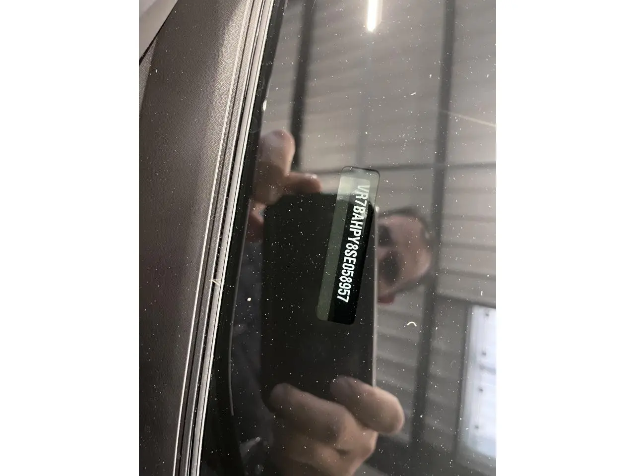 Gros plan sur le pare-brise noir métallisé d'une Citroën C4 2025 montrant le numéro VIN à travers la vitre.