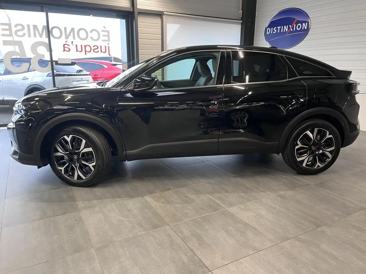 Profil droit d'une Citroën C4 noire métallisée 2025 avec jantes alliage 18'' et rétroviseurs noirs brillants en showroom.