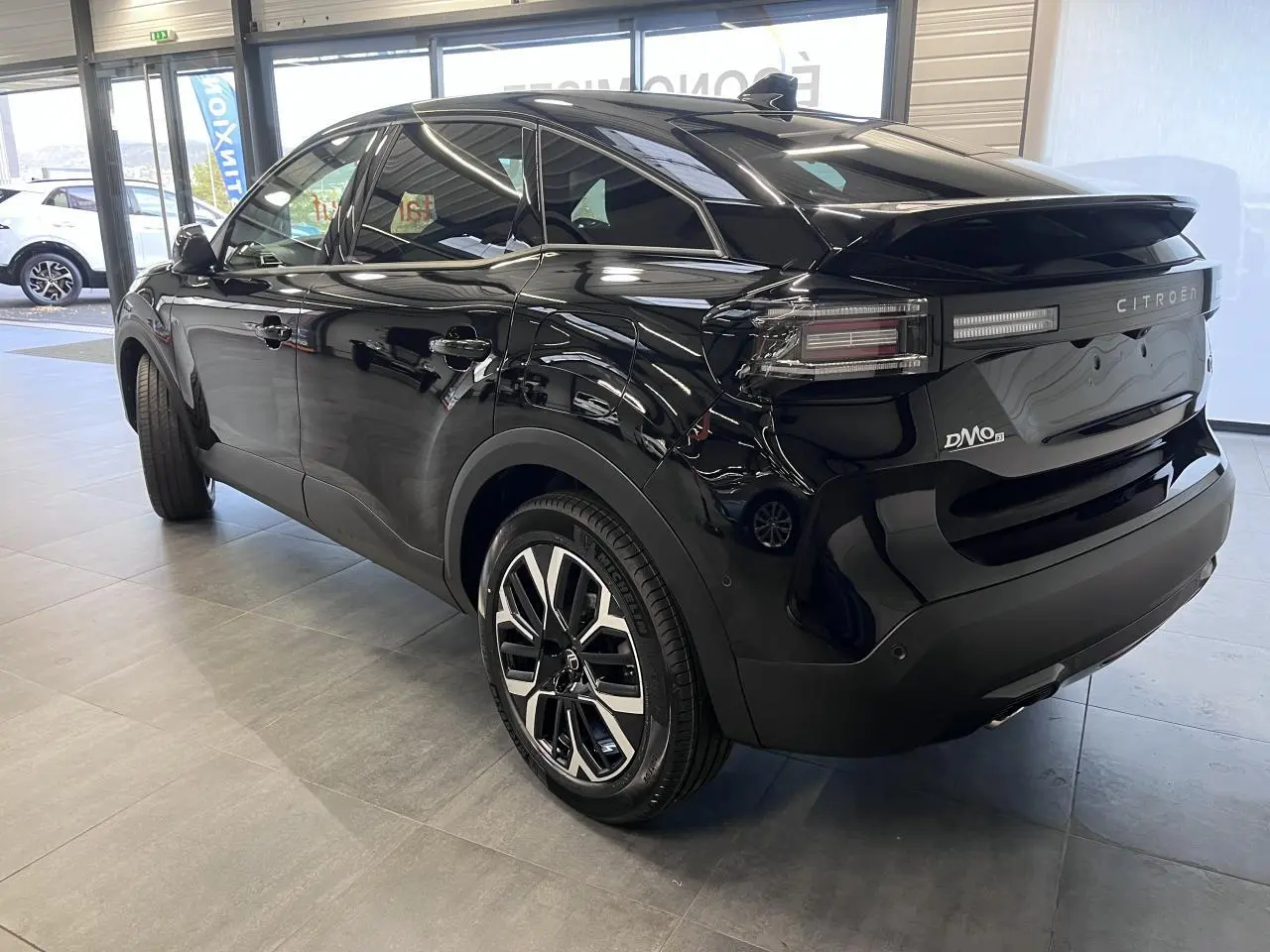 Vue 3/4 arrière droite d'une Citroën C4 noire métallisée avec jantes alliage et feux LED distinctifs.