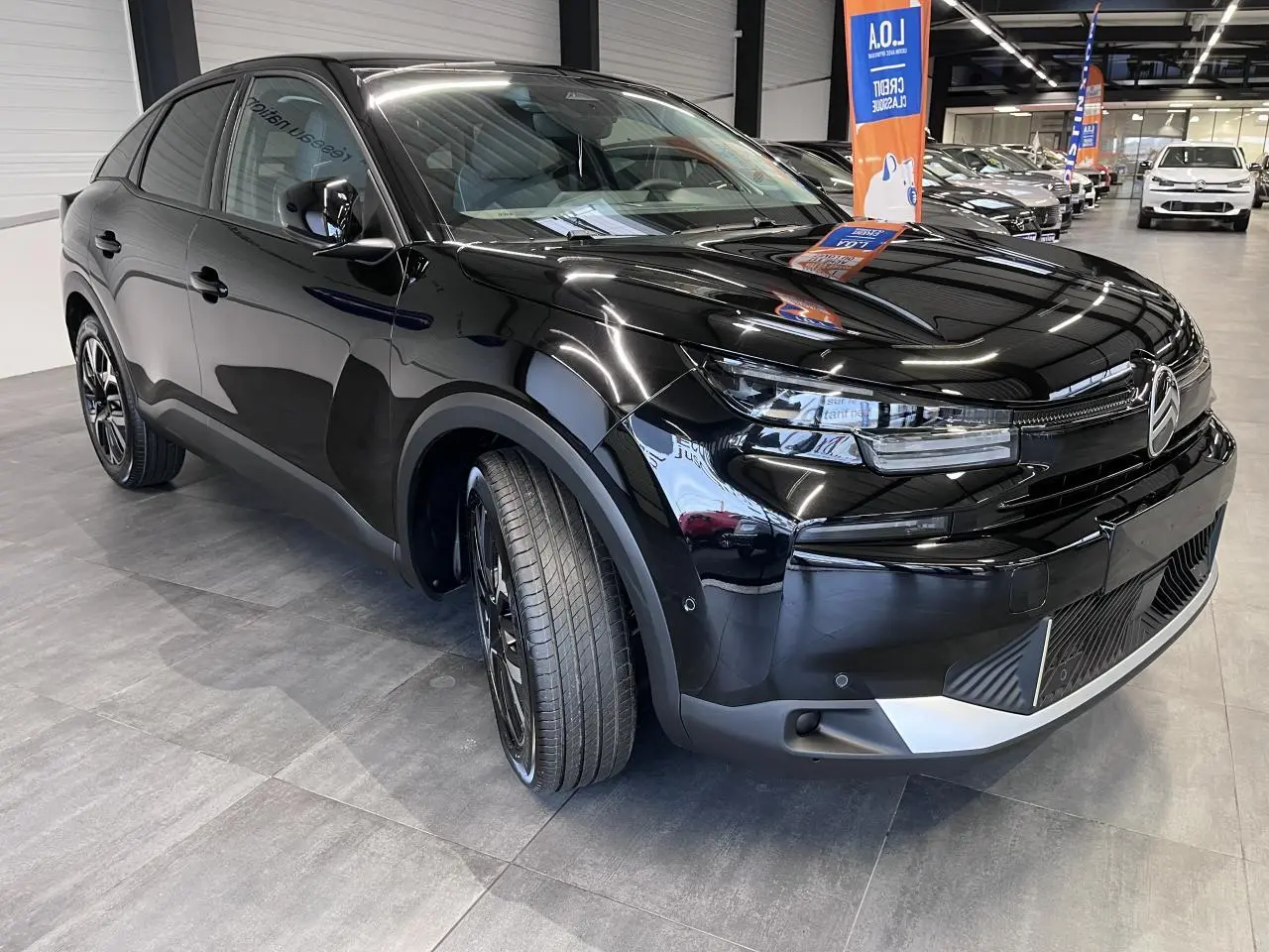 Citroën C4 hybride noire métal vue 3/4 avant droit avec jantes alliage et calandre distinctive.