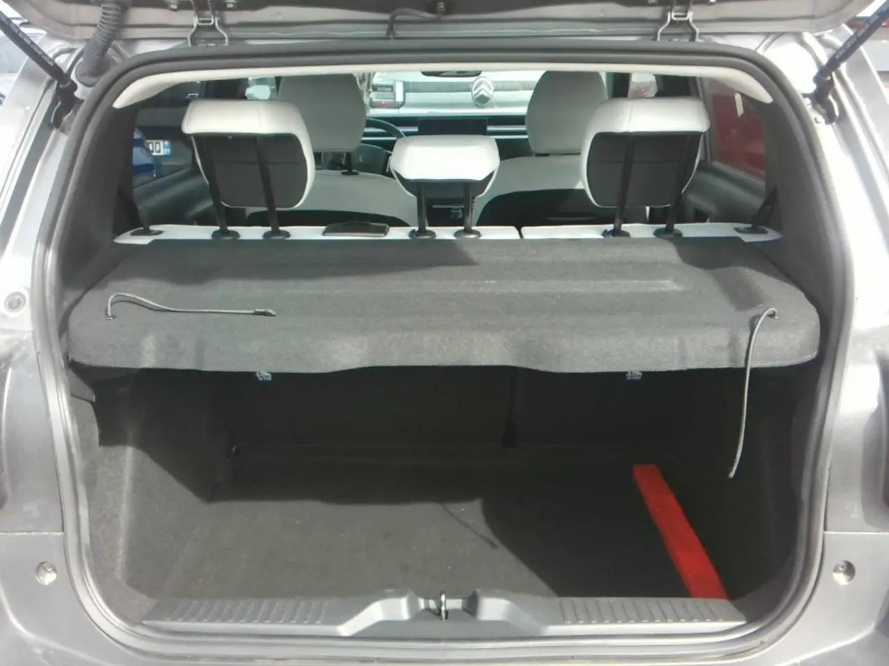 Vue arrière du coffre ouvert d'une Citroën C3 gris Mercury, montrant les appuie-têtes blancs et la tablette arrière.