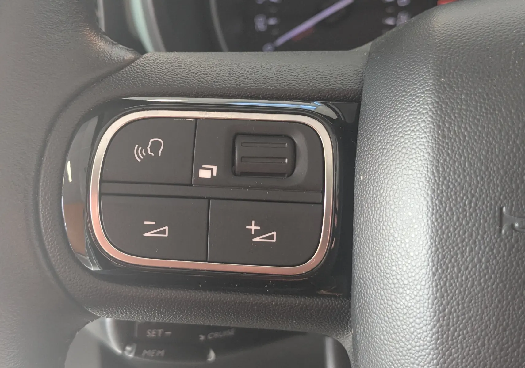 Gros plan sur les commandes de volume et téléphone intégrées au volant du Citroën Berlingo beige 2019.