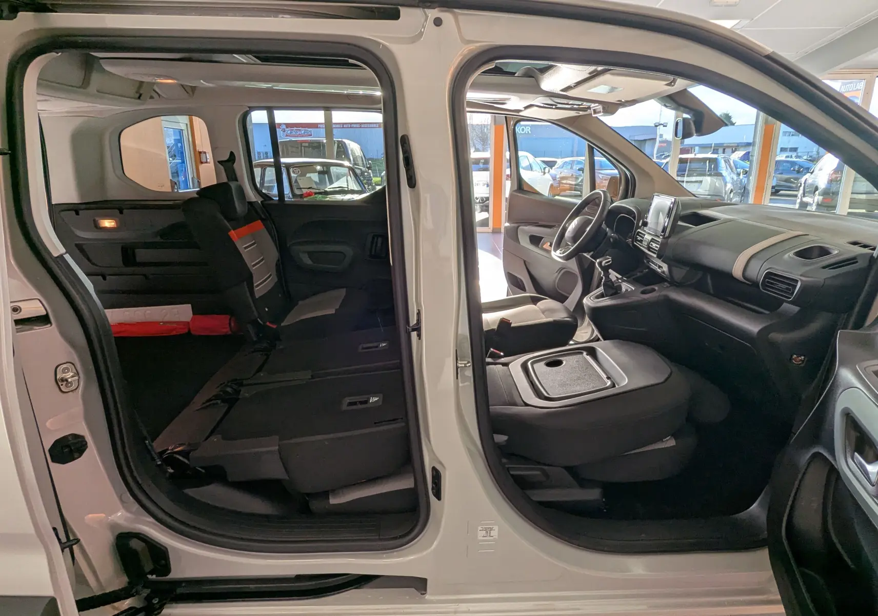 Vue latérale gauche intérieure du Citroën Berlingo beige 2019 avec portes ouvertes et sièges arrière rabattus.