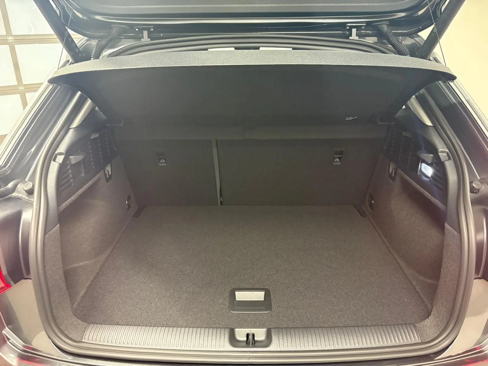 Coffre ouvert d’un Audi Q2 35 TFSI S Line gris Daytona, vue arrière montrant l’espace de chargement vide et la tablette cache-bagages.