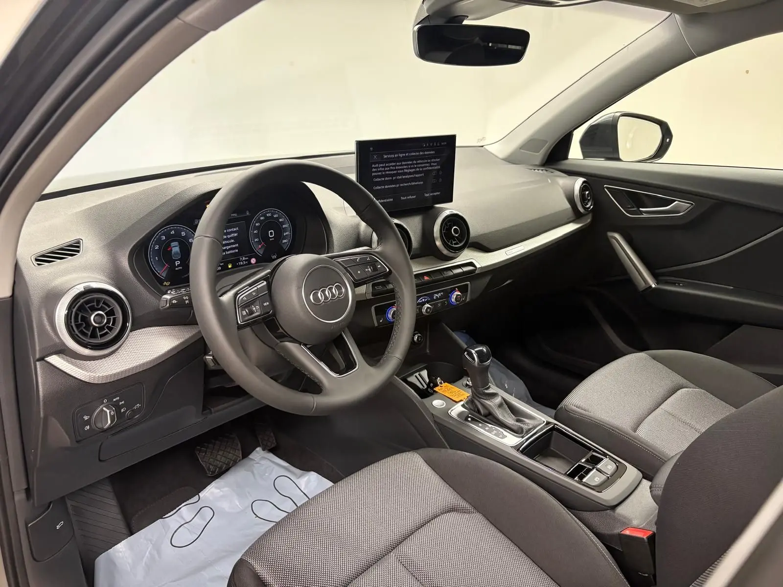 Vue intérieure côté conducteur de l'Audi Q2 35 TFSI 150 S tronic 7 S line avec tableau de bord moderne et sièges gris.