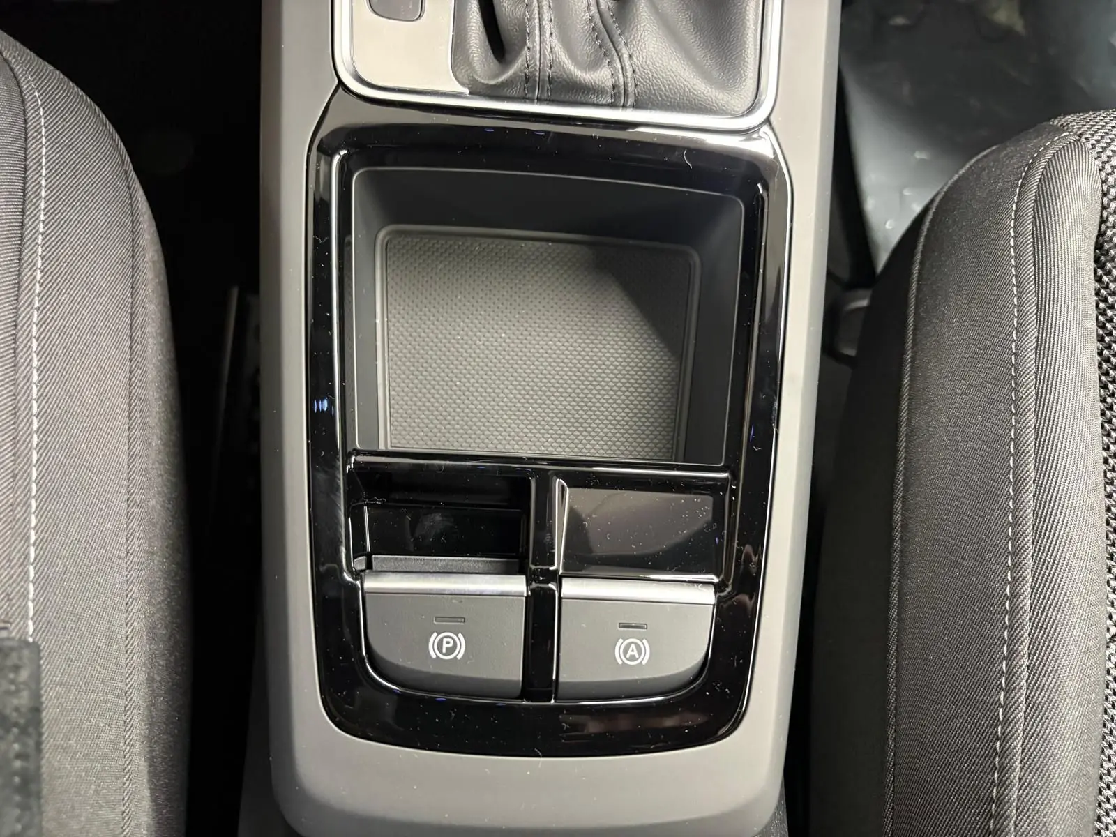 Vue plongeante sur la console centrale noire de l'Audi Q2 35 TFSI S Line avec boutons de frein à main et auto hold.