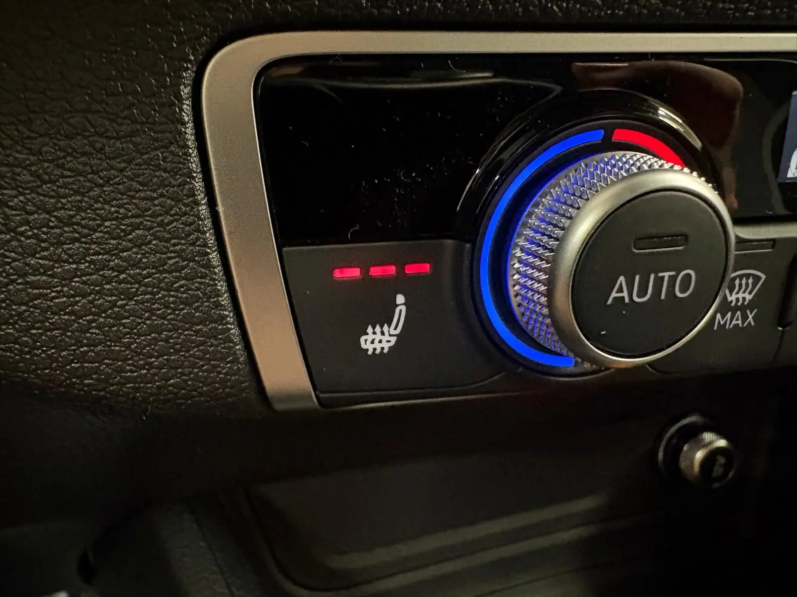 Gros plan sur la commande de siège chauffant et régulation automatique de la climatisation dans l'Audi Q2 Gris Daytona.