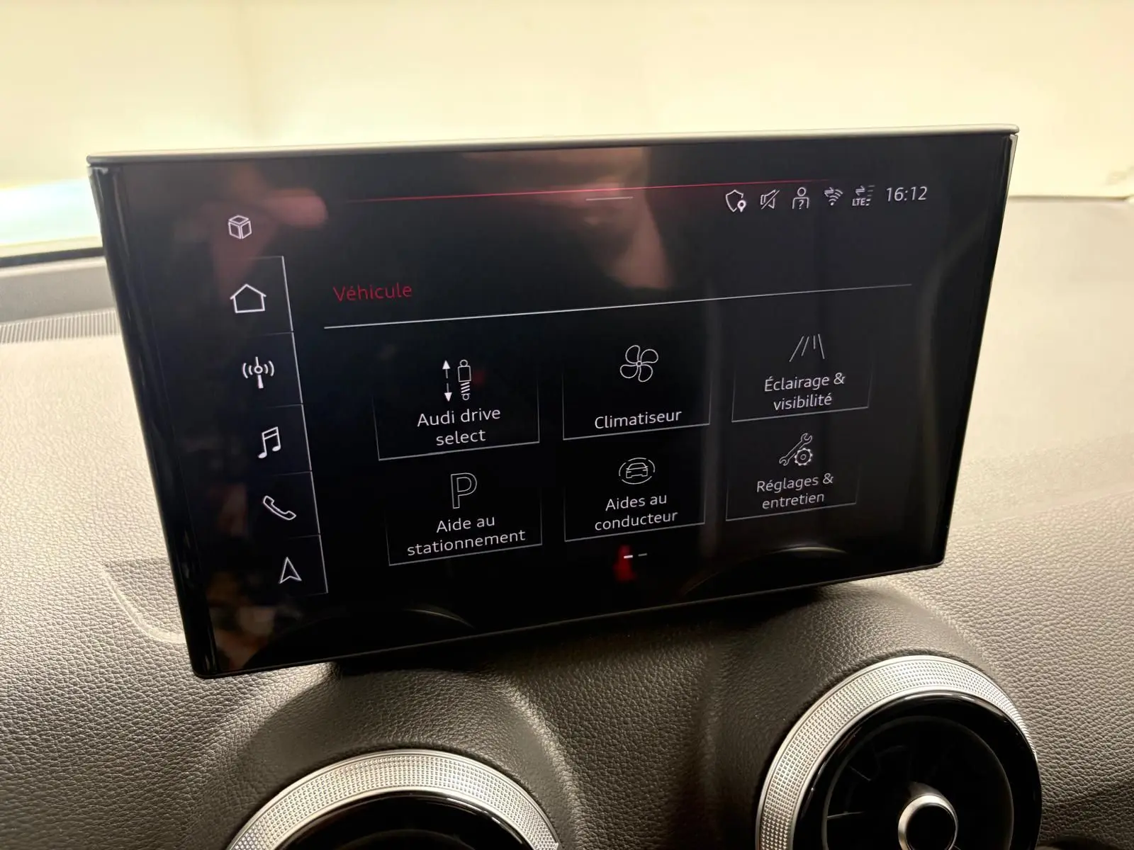 Écran tactile central de l’Audi Q2 35 TFSI S Line 2026 affichant les réglages du véhicule, avec deux aérateurs ronds en dessous.