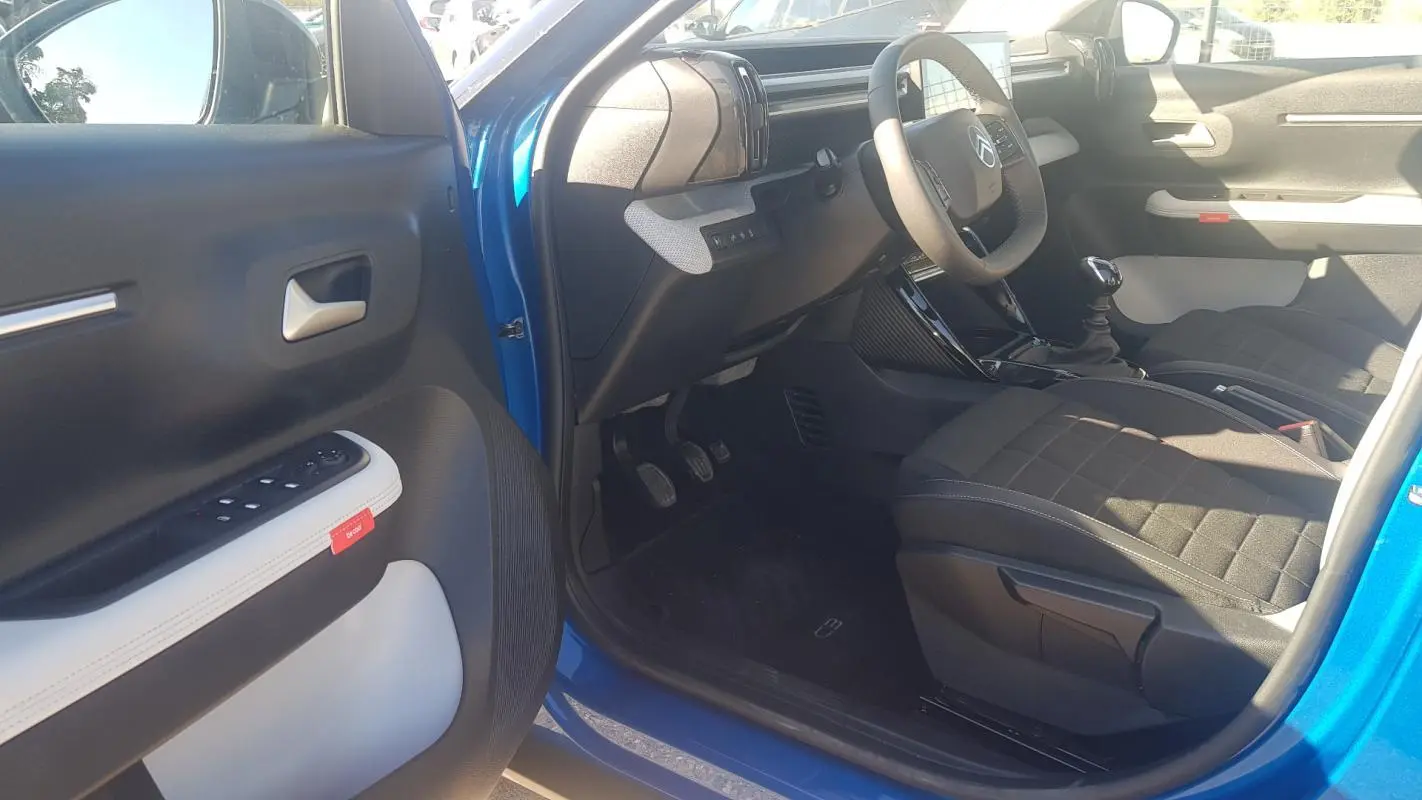 Intérieur avant droit d'une Citroën C3 bleu foncé 2024, montrant siège tissu noir et tableau de bord moderne.