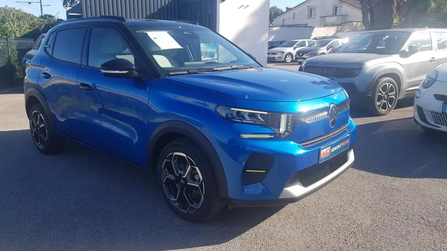 Citroën C3 bleu foncé vue 3/4 avant droit, avec jantes alliage 17 pouces et barres de toit noires.