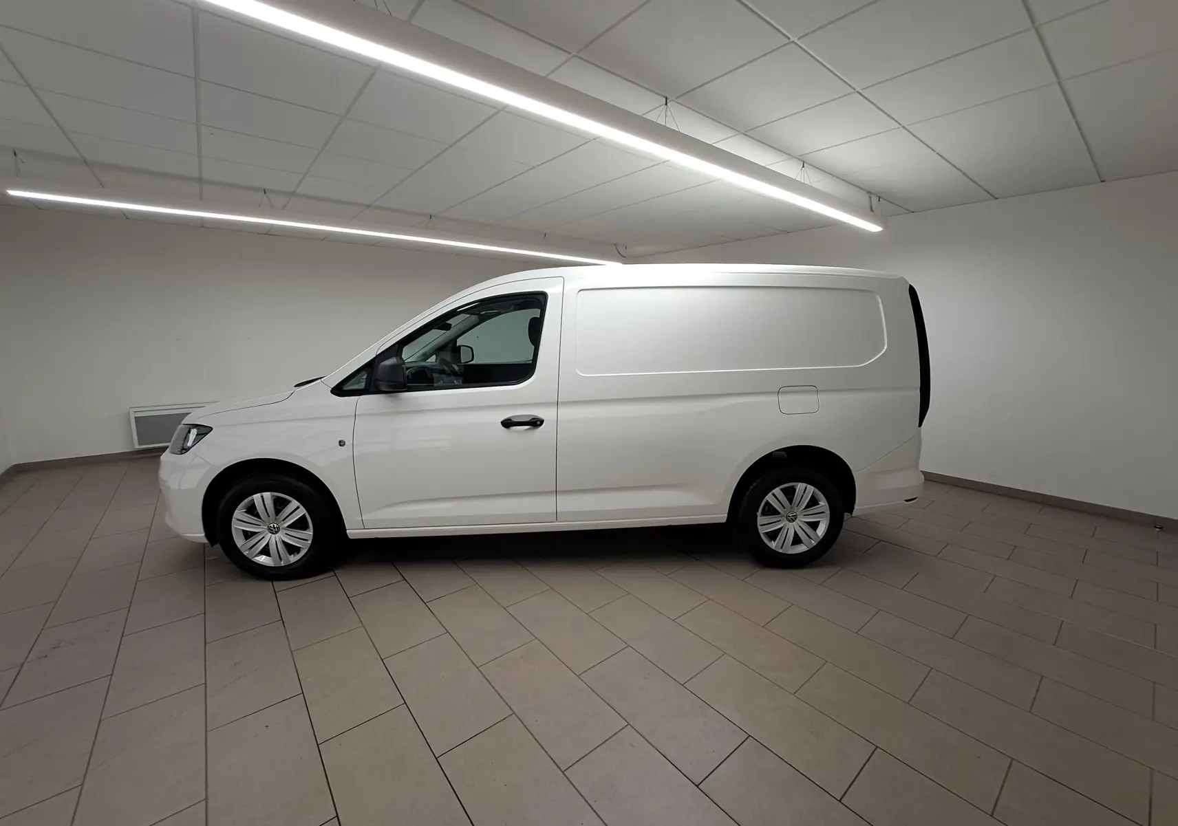 Vue de profil côté gauche du Volkswagen Caddy Cargo Maxi blanc candy 2026 dans un intérieur neutre.