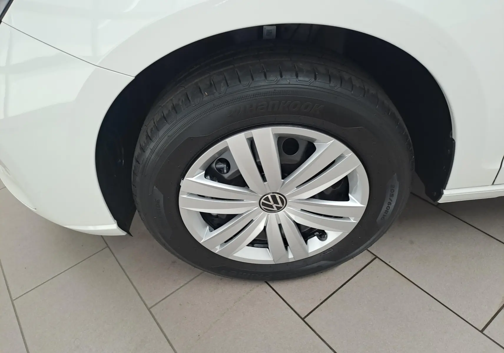 Gros plan sur la roue avant gauche blanche du Volkswagen Caddy Cargo Maxi 2026 avec jante argentée et pneu Hankook.