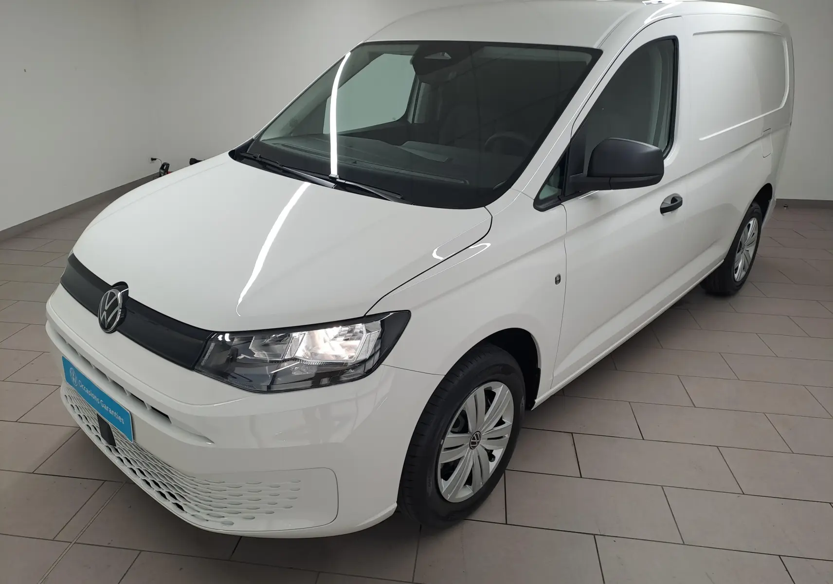 Vue 3/4 avant droit d’un Volkswagen Caddy Cargo Maxi blanc Candy avec calandre noire et jantes acier.