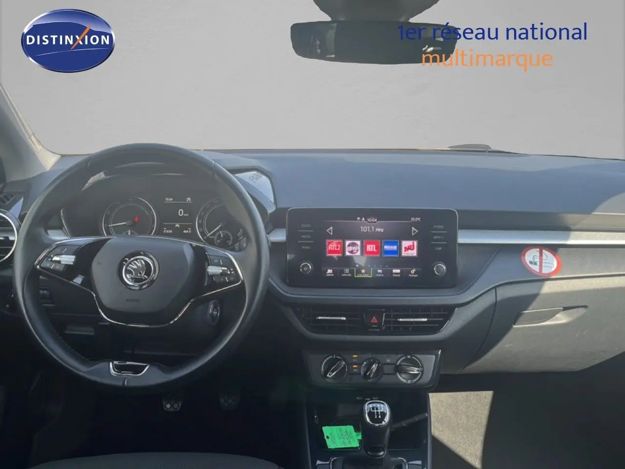 Vue intérieure avant du tableau de bord d'une Skoda Fabia blanche avec volant cuir et écran tactile central.