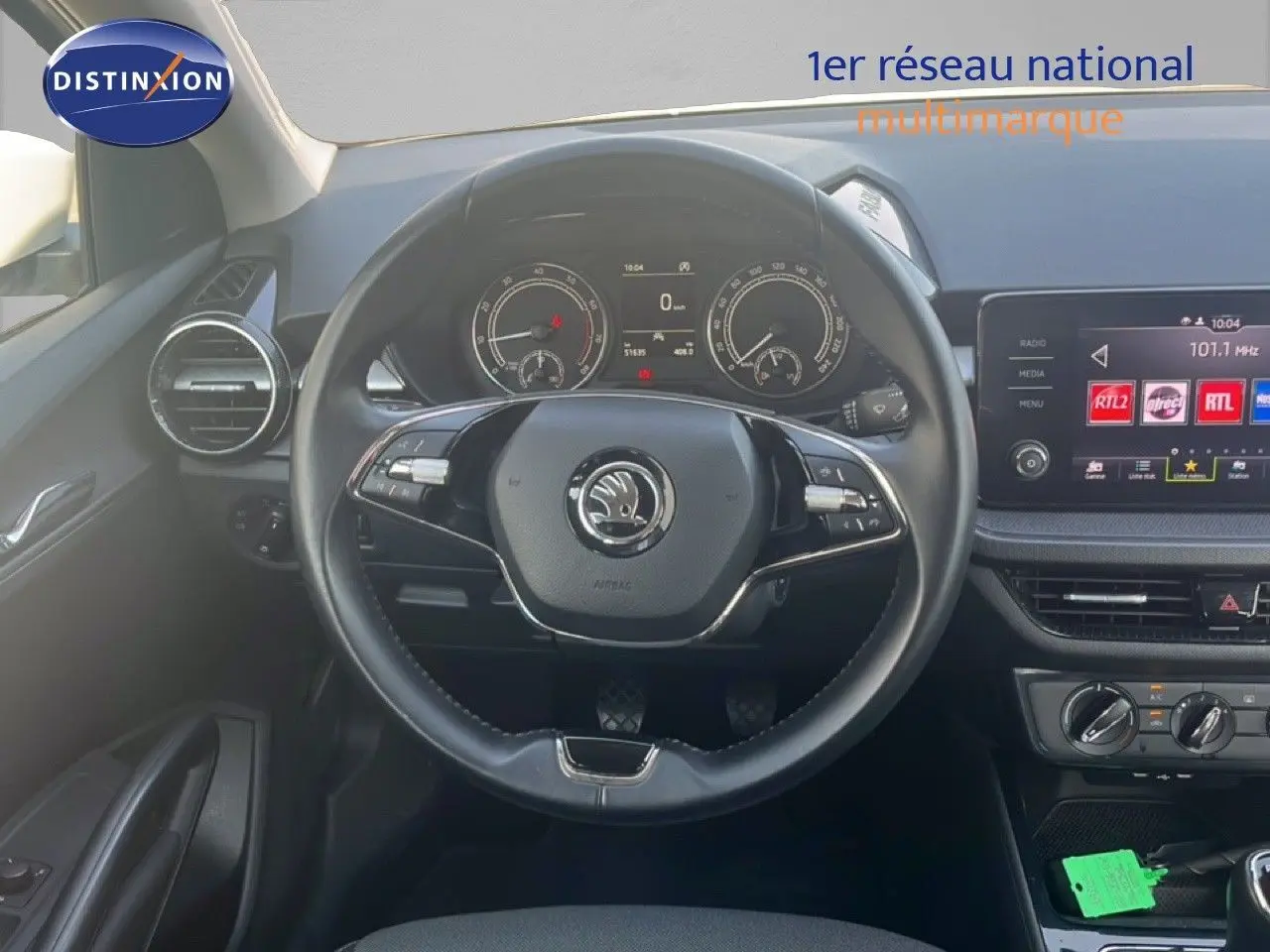 Vue intérieure centrée sur le volant noir et le tableau de bord numérique d'une Skoda Fabia 2022 blanche.