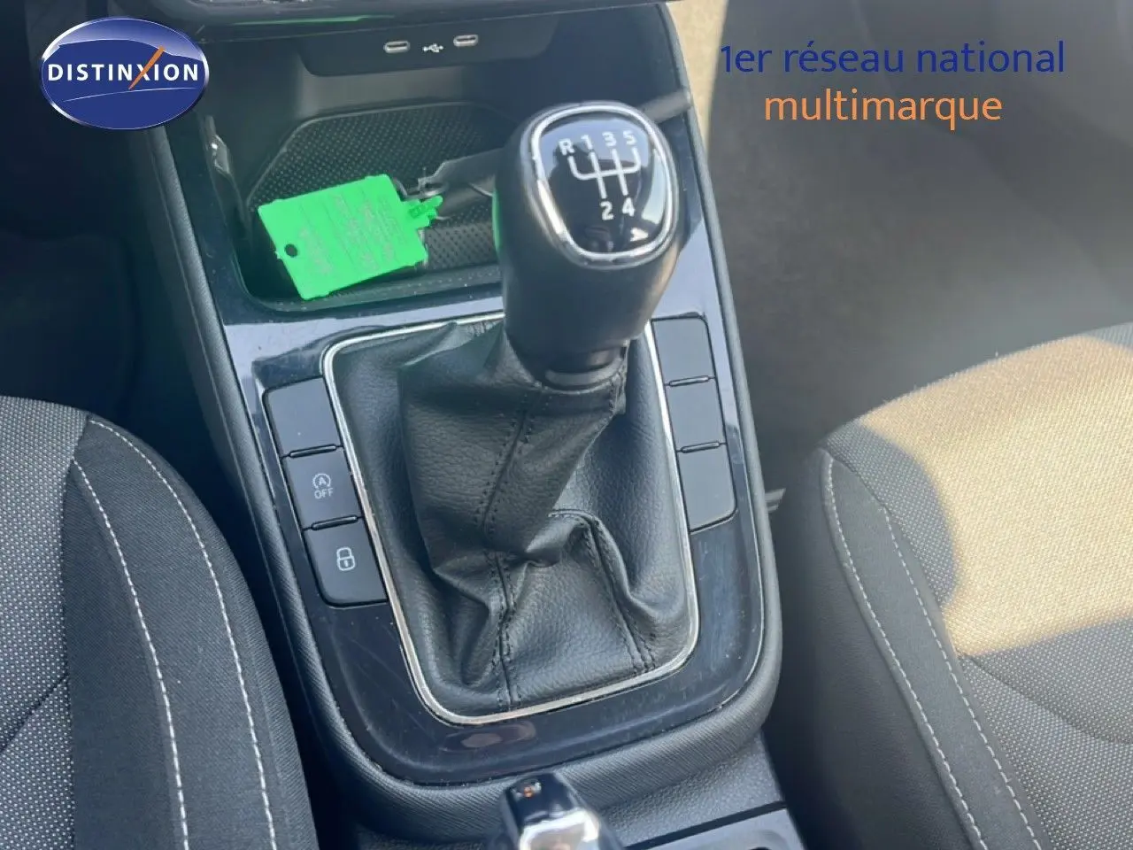 Gros plan sur la boîte manuelle noire et la console centrale de la Skoda Fabia blanche, avec sièges en tissu gris.