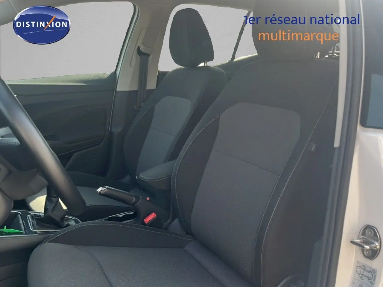 Vue intérieure côté conducteur de la Skoda Fabia blanche, mettant en valeur les sièges en tissu noir et gris.