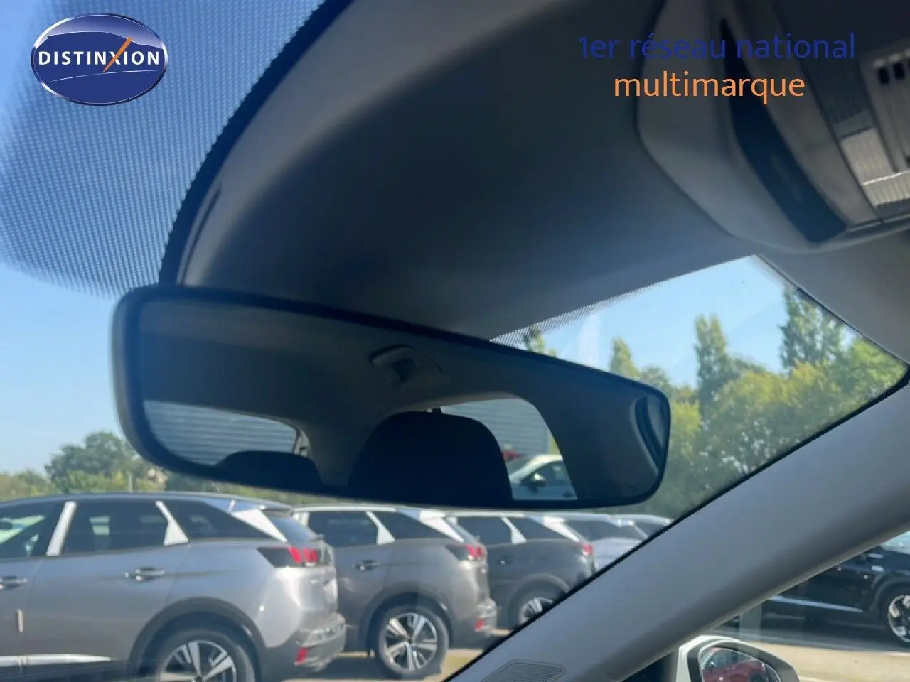 Vue intérieure montrant le rétroviseur central d'une Skoda Fabia blanche Candy, avec plusieurs SUV gris en arrière-plan.