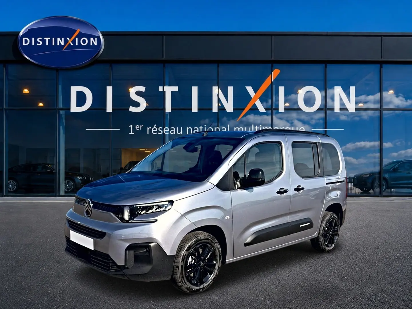 Citroën Berlingo Steel Grey en 3/4 avant droit, avec jantes noires et barres de toit visibles devant showroom Distinxion.