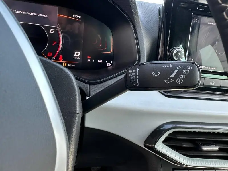 Gros plan sur le commodo d’essuie-glace et le tableau de bord numérique d’une SEAT Ibiza 2025, intérieur gris clair.