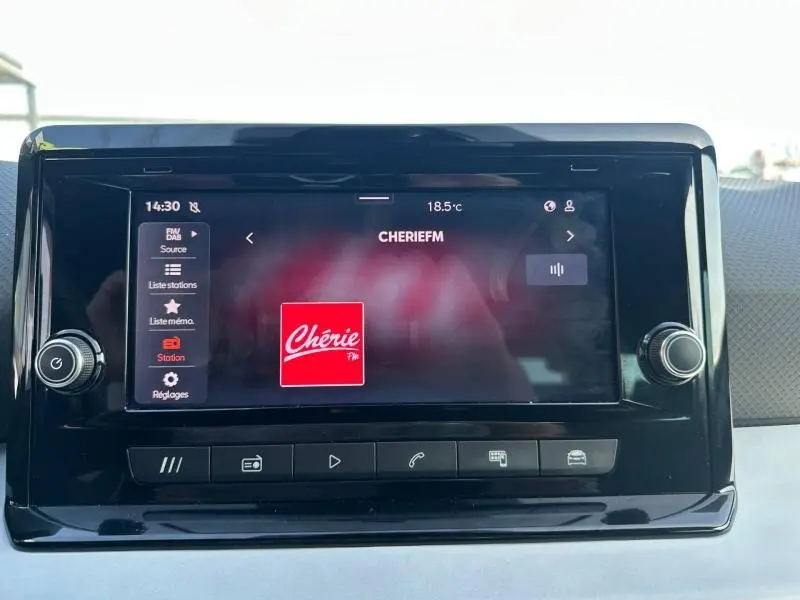 Écran tactile central du tableau de bord de la SEAT Ibiza 2025 affichant la radio Chérie FM, avec commandes physiques autour.