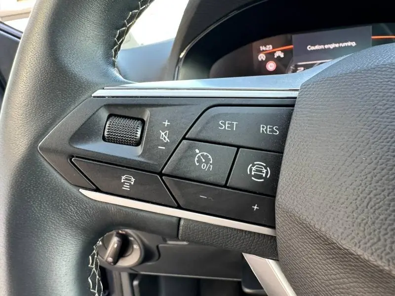 Gros plan sur les commandes de régulateur de vitesse au volant cuir d'une SEAT IBIZA 2025 gris métallisé.