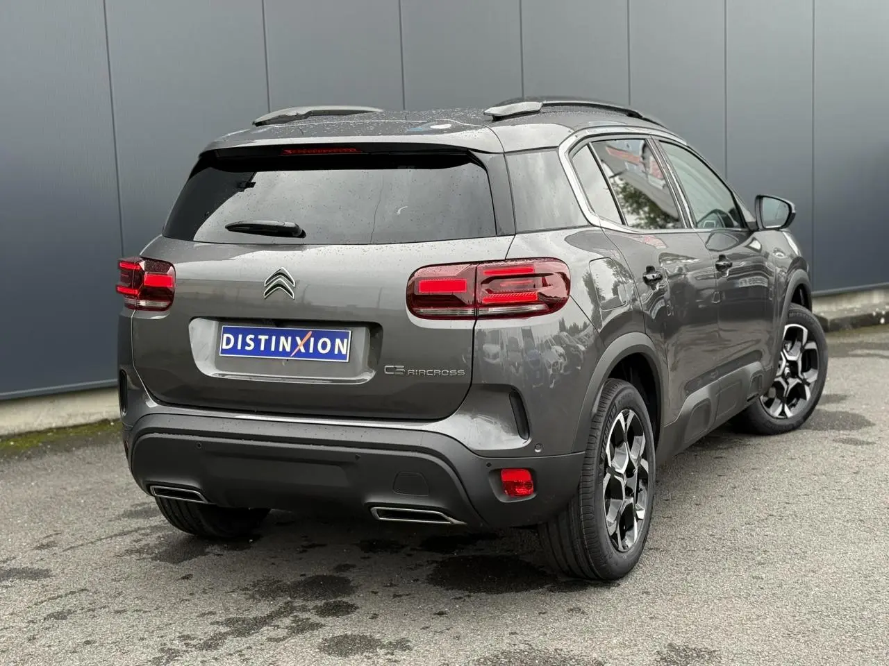 Vue 3/4 arrière droite d'un Citroën C5 Aircross gris Platinium avec toit noir et jantes alliage bi-ton.
