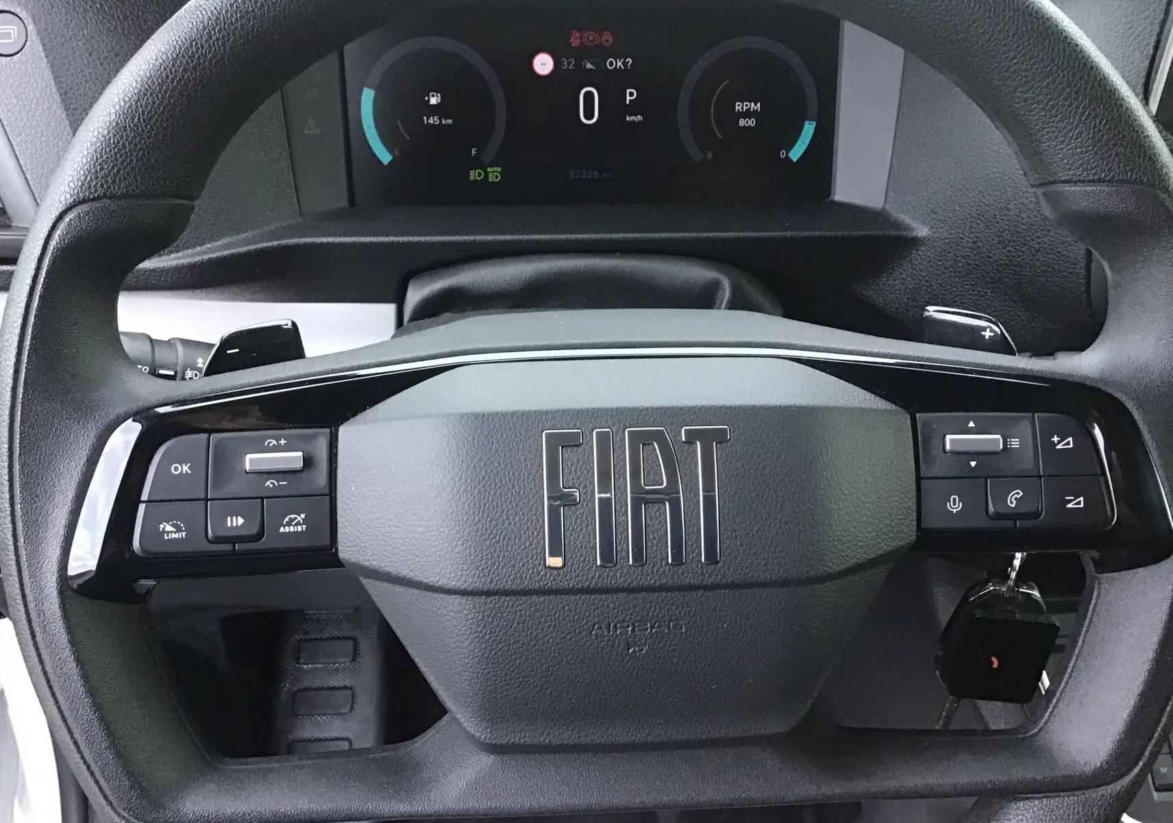 Volant noir avec logo FIAT en gros plan, tableau de bord digital affichant vitesse et compte-tours du fourgon blanc FIAT Scudo 2024.