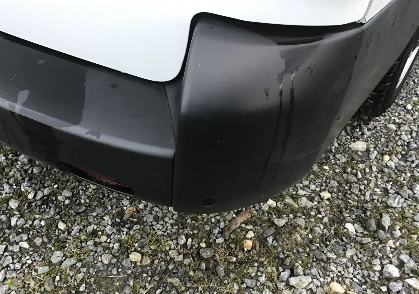 Gros plan sur l'angle arrière droit du pare-chocs noir du FIAT Scudo Fourgon blanc, avec traces d'usure visible.