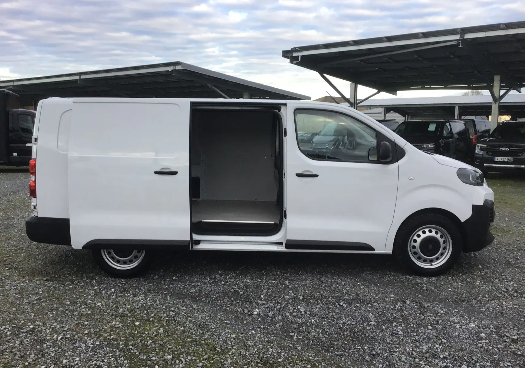 Vue de profil côté droit d'un FIAT Scudo Fourgon blanc 2024 avec porte coulissante ouverte et garde au sol rehaussée.