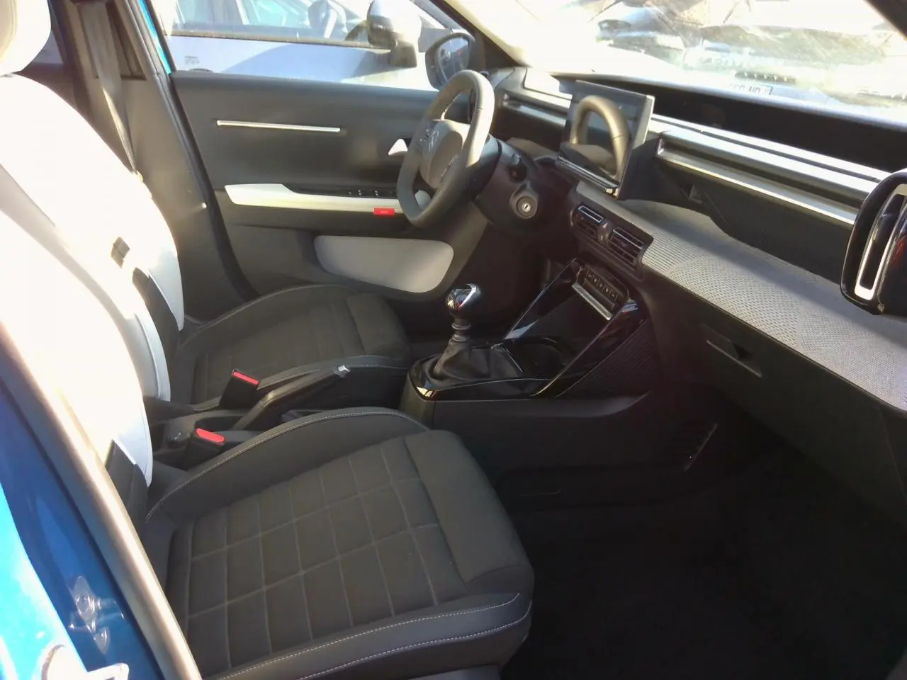 Vue intérieure côté conducteur de la Citroën C3 Bright Blue avec tableau de bord moderne et boîte manuelle.