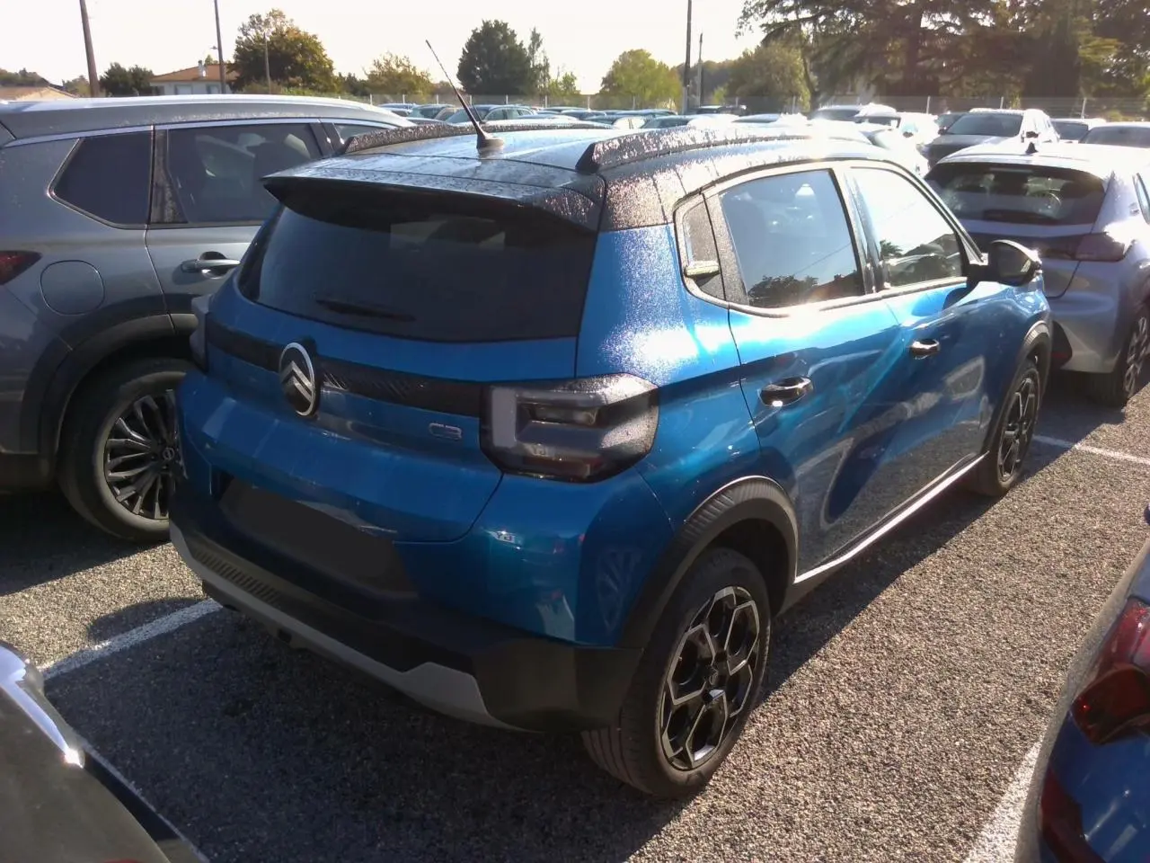 Vue 3/4 arrière droite d'une Citroën C3 2025 Bright Blue avec toit noir Perla et jantes alliage noires.