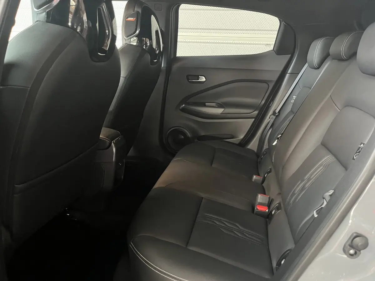 Vue intérieure côté droit des sièges arrière en cuir noir du Nissan Juke Hybrid 2024, avec détails des appuie-têtes et portières.