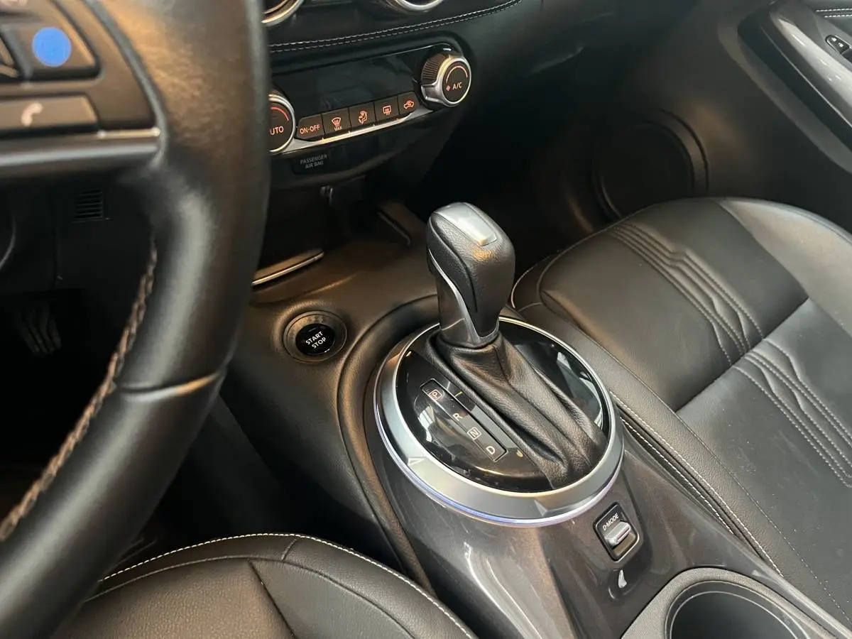 Vue intérieure rapprochée du levier de vitesse automatique et siège en cuir noir du Nissan Juke Hybrid 2024 côté droit.
