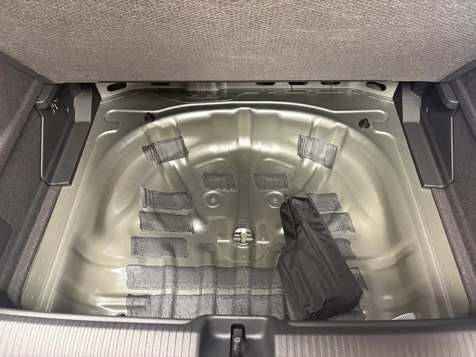 Coffre ouvert d’un Audi Q2 35 TFSI 150 S tronic 7 S line 2026, montrant le logement métallique de la roue de secours.