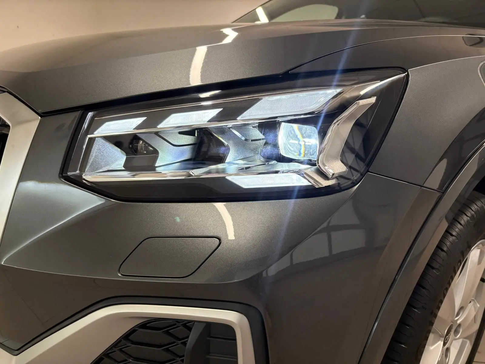 Gros plan sur le phare avant droit de l'Audi Q2 35 TFSI S Line en gris Daytona métallisé.